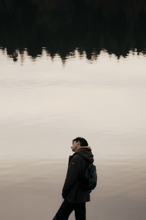A candid moment of a person reflecting by a calm lake.