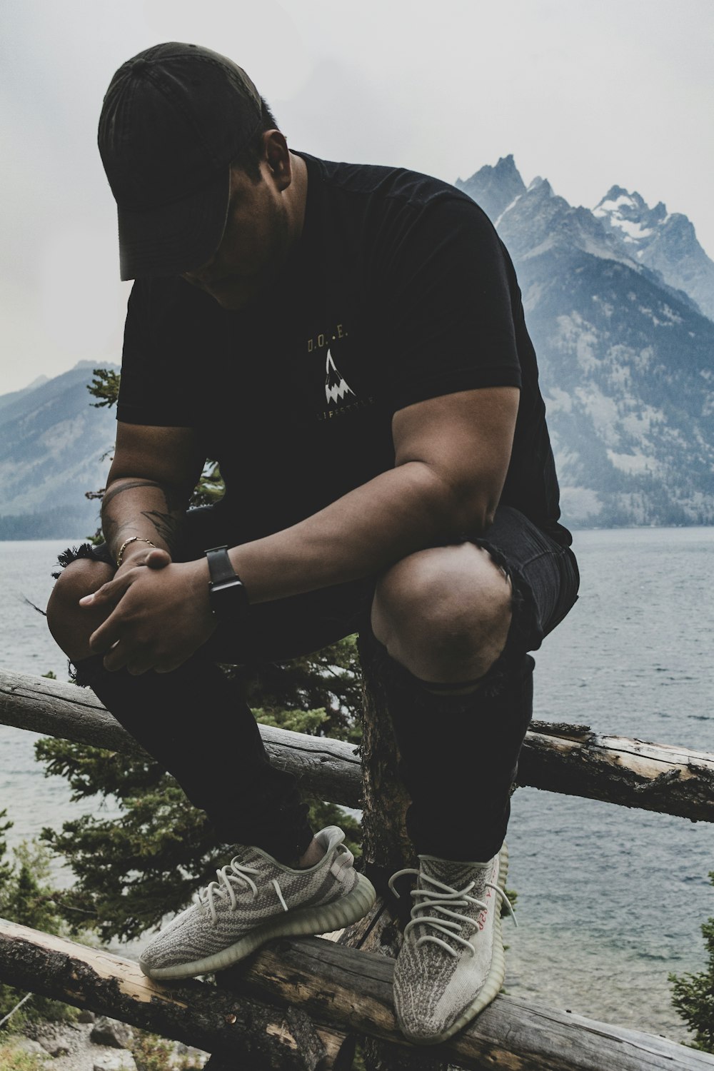 man wearing black crew-neck shirt sitting on fence