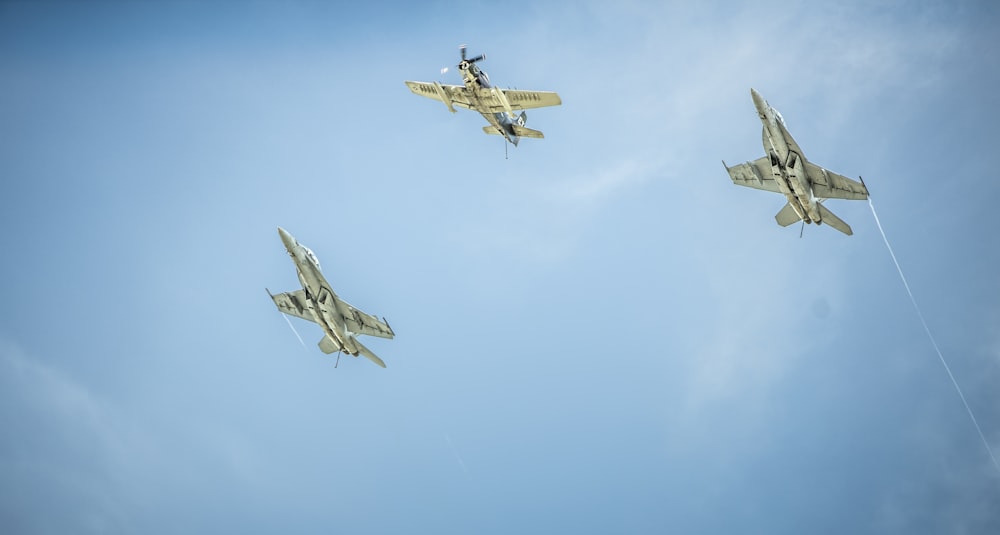 three gray-and-black jet planes under clouds