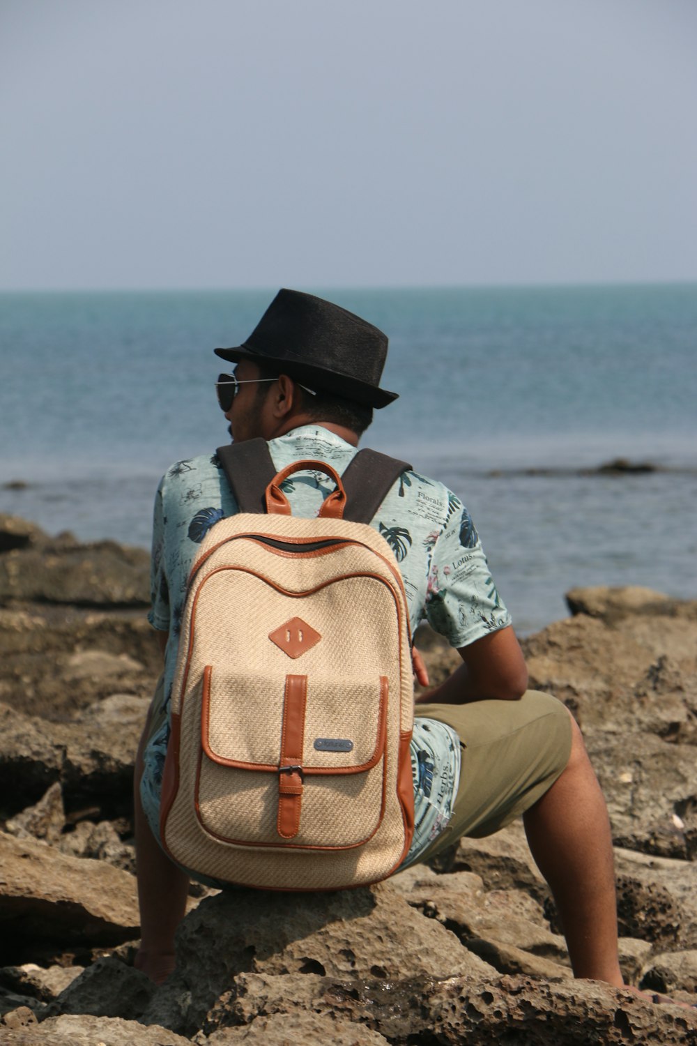 man sitting on rocky shore during daytime