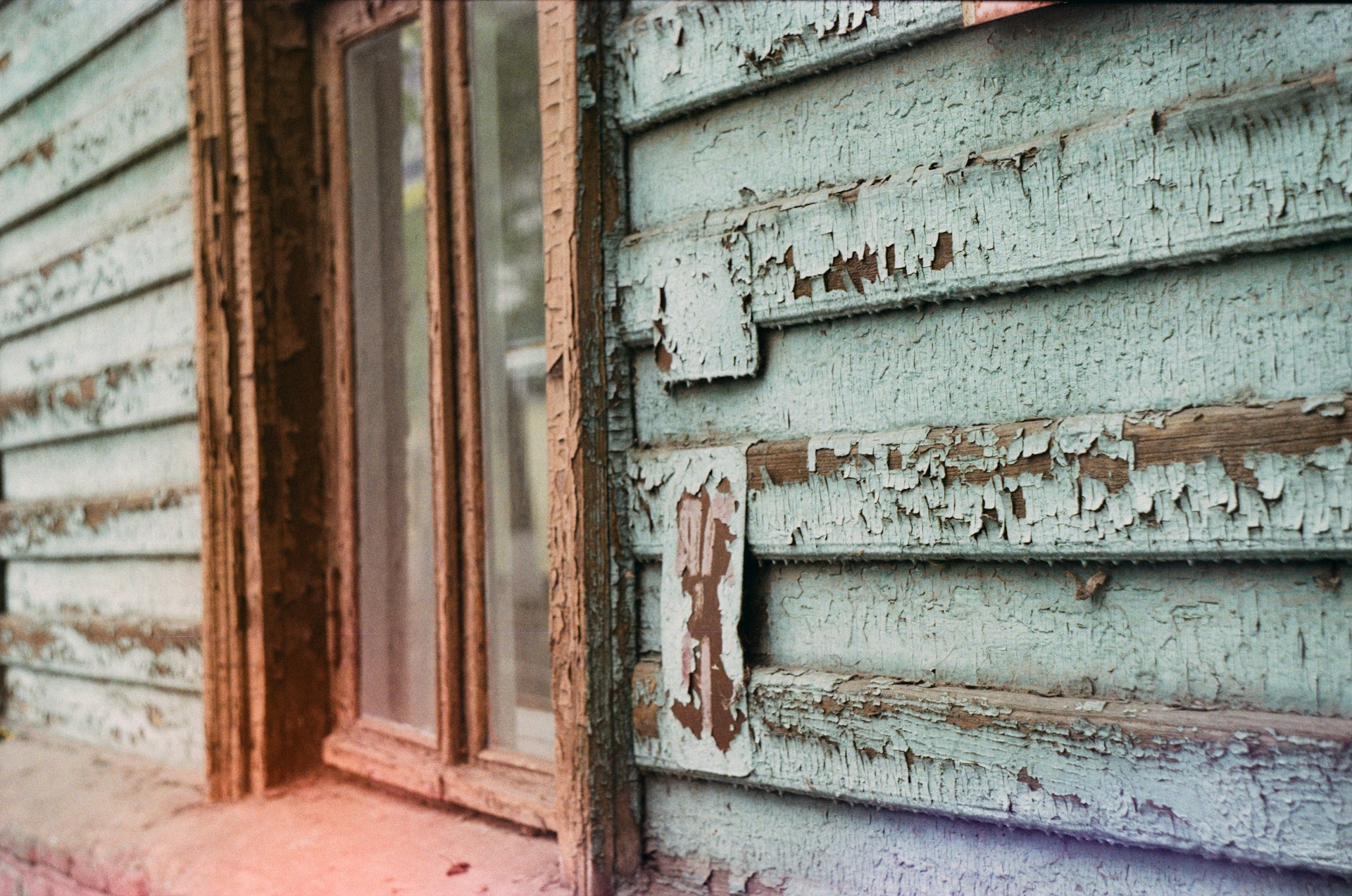 A close-up shot capturing the intricate textures of peeling paint and aged wood on the house's exterior.