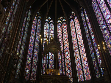 Elegant stained glass windows casting colorful patterns inside a solemn worship space.