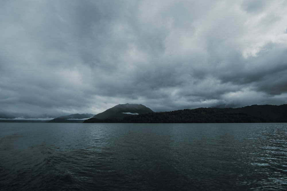 silhouette of mountain across calm body of water