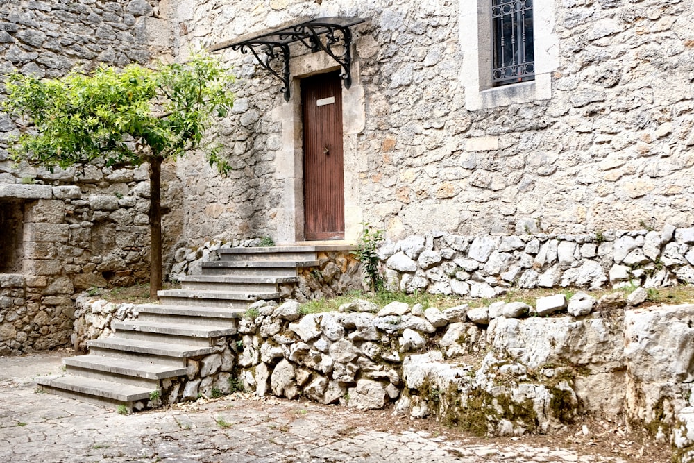 closed brown wooden door of grey rock building