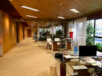 black monitor on table near printer paper on office area of the building with no people