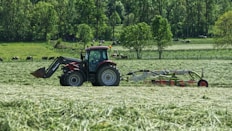 red tractor with farming attachment on field during daytime