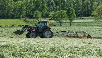 red tractor with farming attachment on field during daytime