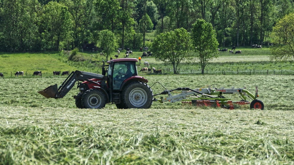 red tractor with farming attachment on field during daytime
