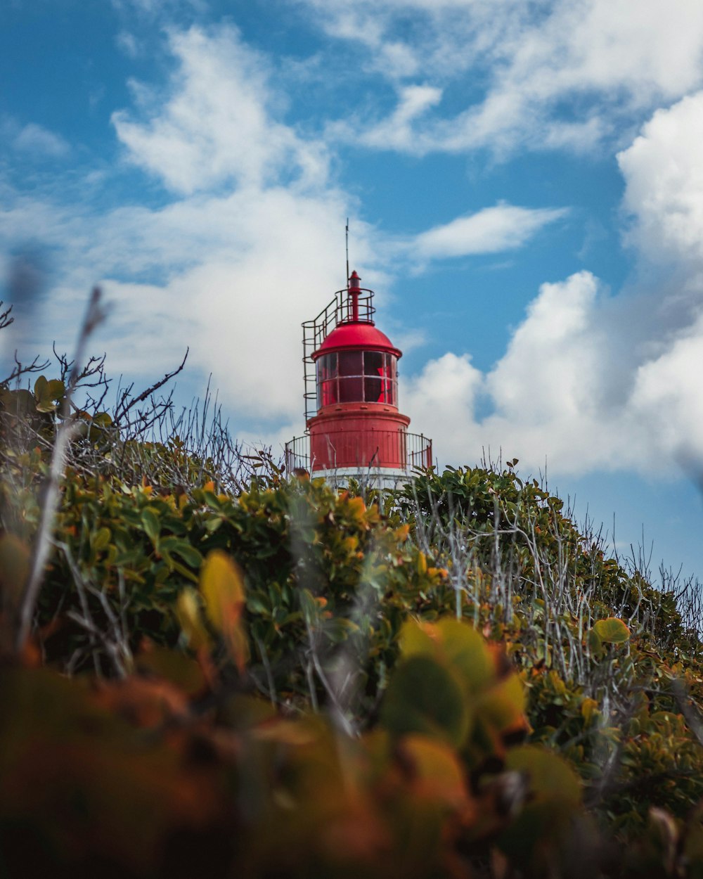 low-angle photography of red tower under blue sky and white clouds