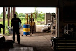 Technicians in protective gear inspecting chemical drums in a clean, organized warehouse.
