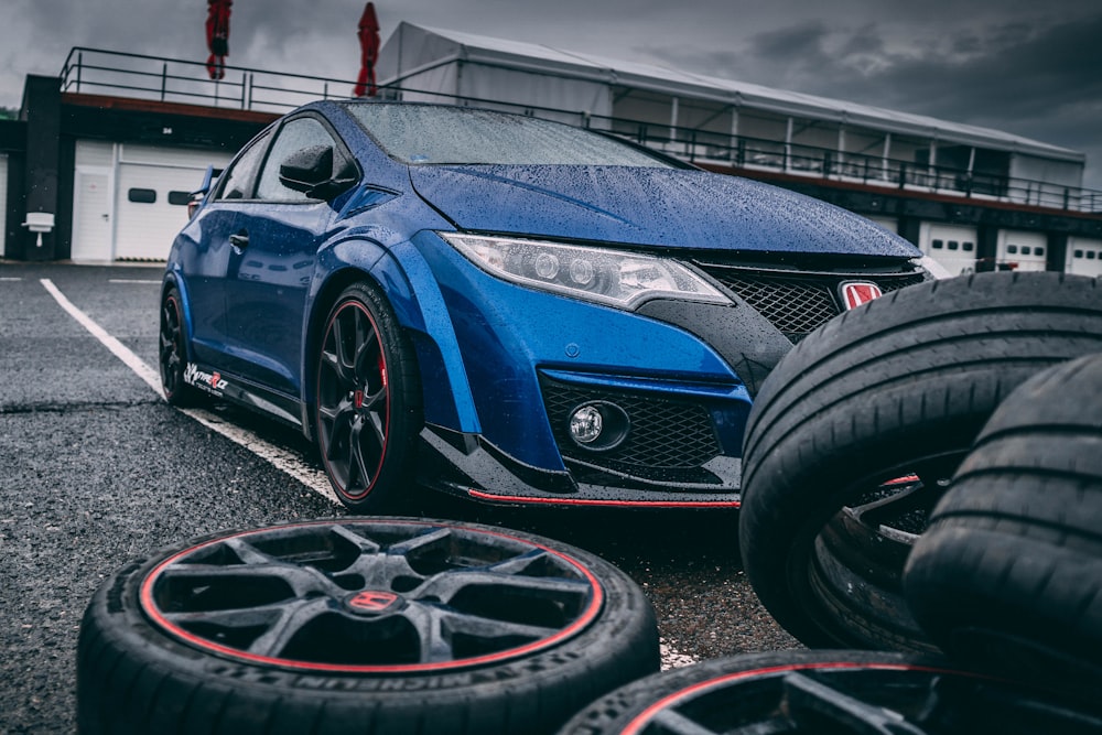 blue Honda vehicle beside vehicle wheel and tire set