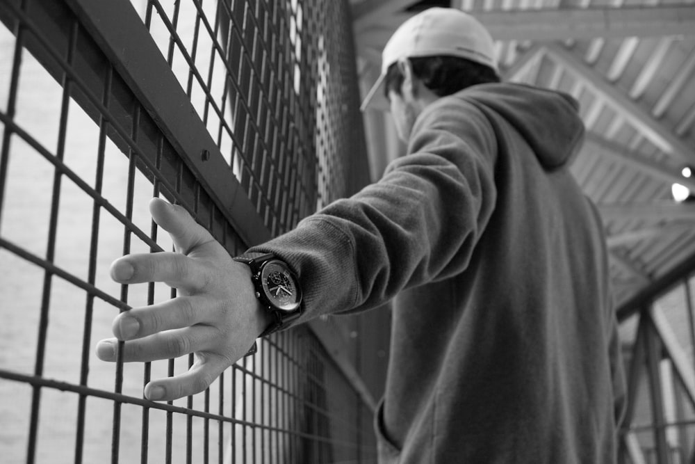 grayscale photography of standing near chain grille