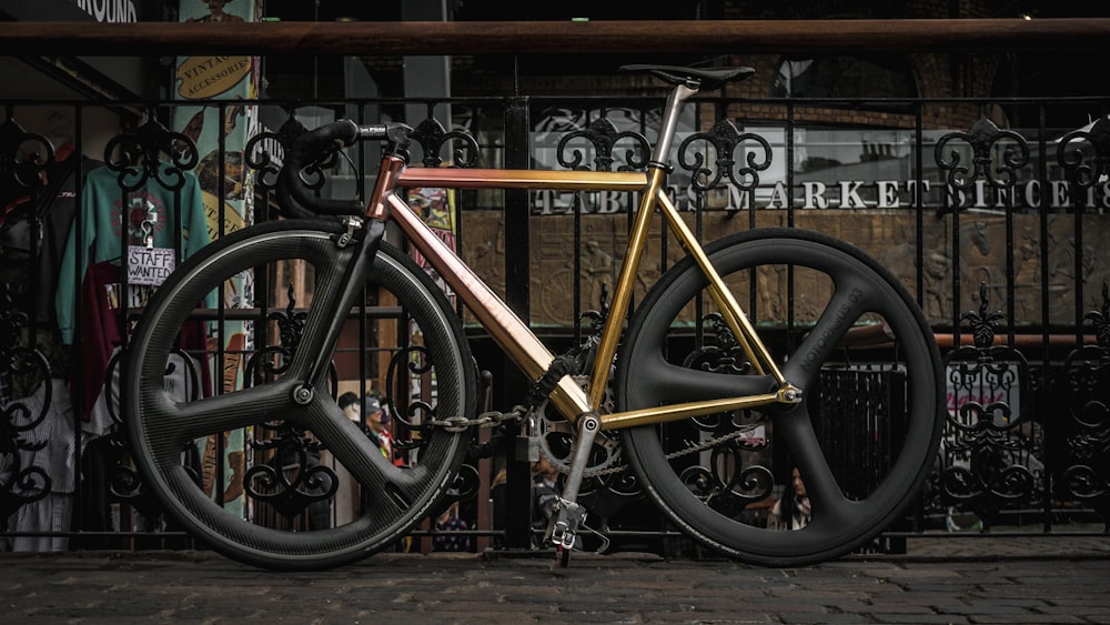 Bicicleta de carretera marrón apoyada en barandillas metálicas grises