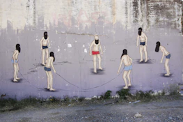 Group photo of six urban artists working together on a large outdoor mural.