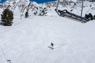 A skier gliding down a snowy mountain slope wearing Laroy LLC skis under a clear blue sky.