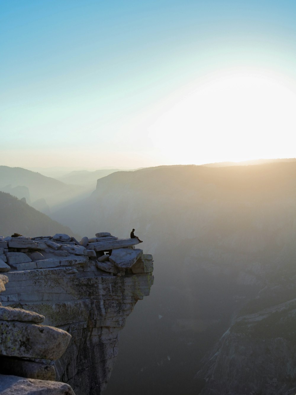 person sitting on rock formation during golden hour