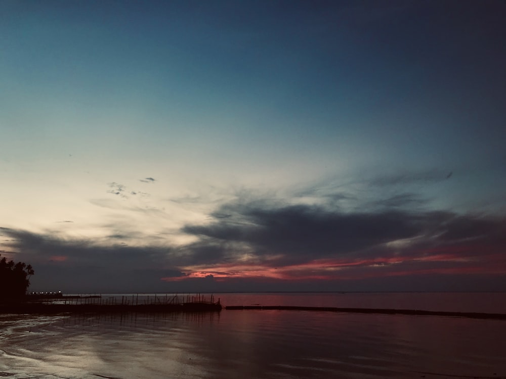 grey and red cloudy sunset sky over lake