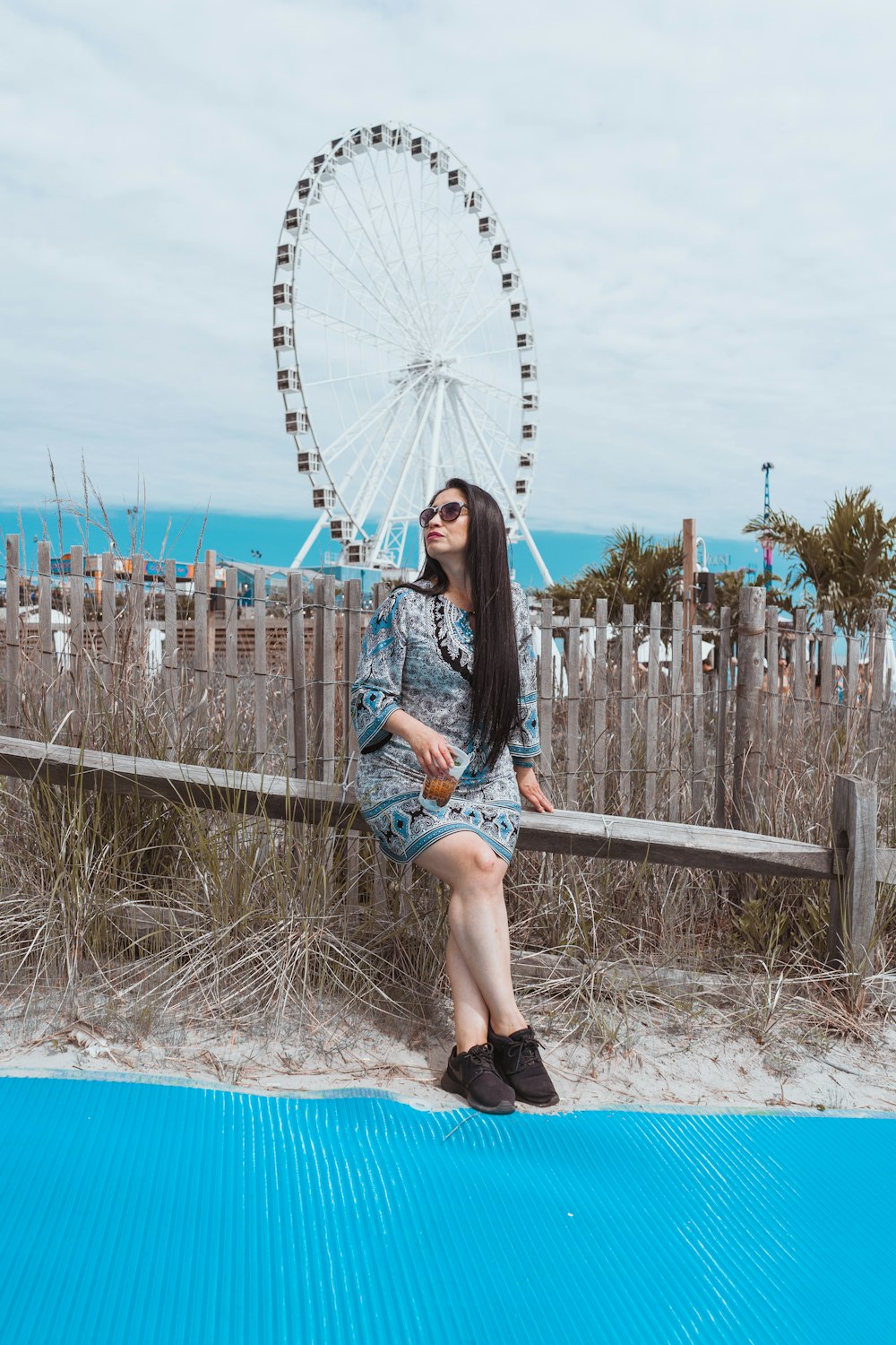 woman sitting on gray fence near Ferris Wheel