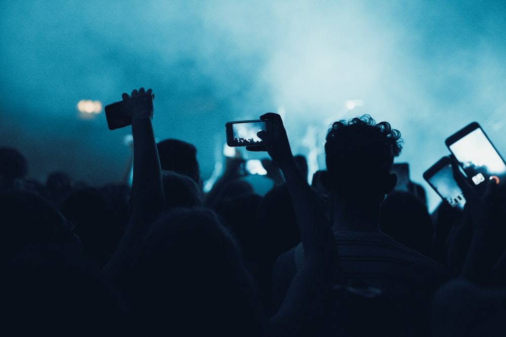 people in dark surface holding smartphones