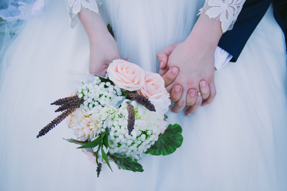 person wearing wedding dress holding bouquet