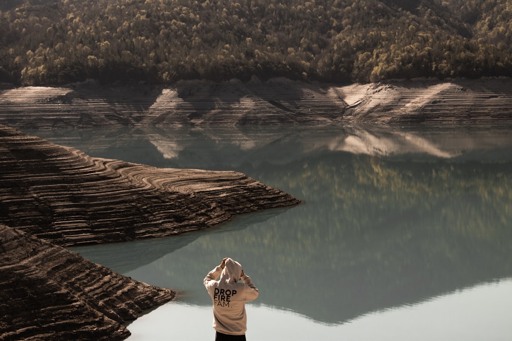 person wearing white hoodie facing calm body of water