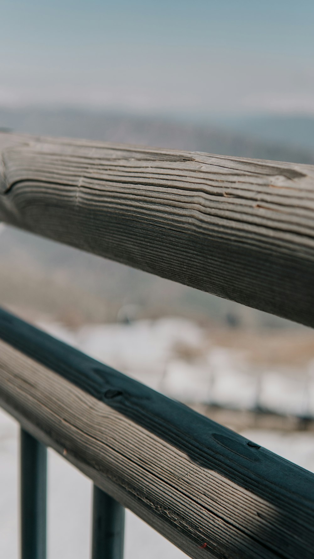a close up of a wooden railing with snow in the background