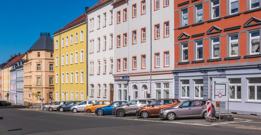 Coches de colores variados aparcados junto a los apartamentos