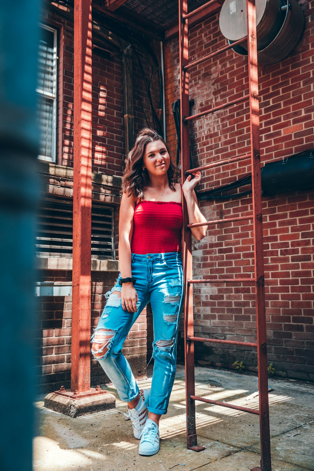 Standing woman in red shirt and blue denim jeans holding onto ladder photo  – Free Apparel Image on Unsplash