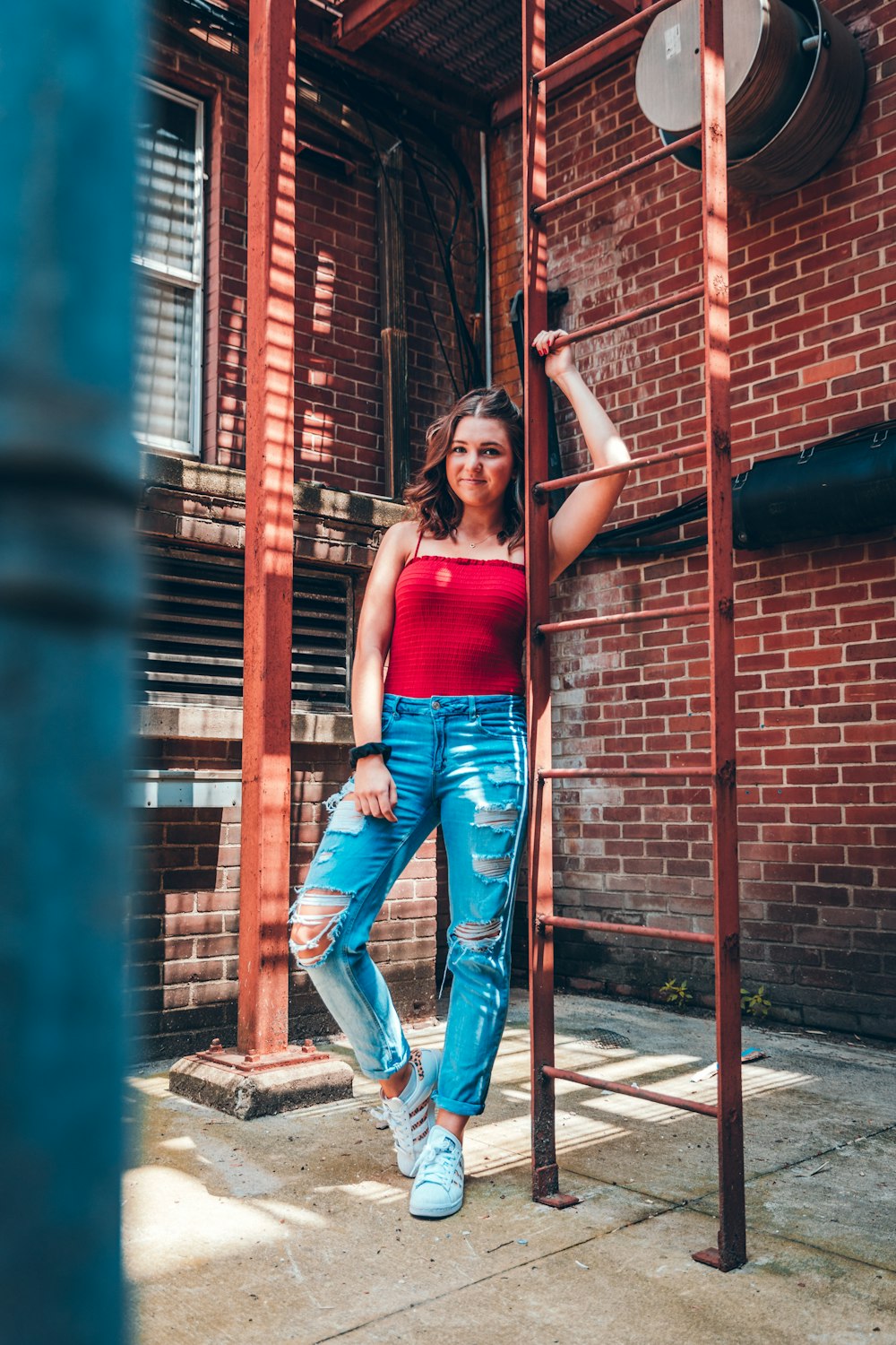 woman leaning beside red metal ladder