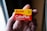 A hand holds a box of Kodak ColorPlus film, displaying the brand name prominently in red and yellow colors. The packaging features details such as 36 exposures and ISO 200. The background is softly blurred, drawing focus to the film box.