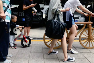 Parent helping their toddler adjust the seat height on a tinywheelz balance bike outdoors.