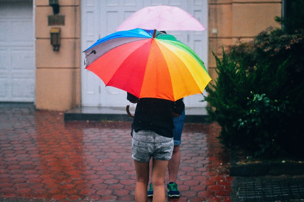 two person under umbrellas outdoor during daytime