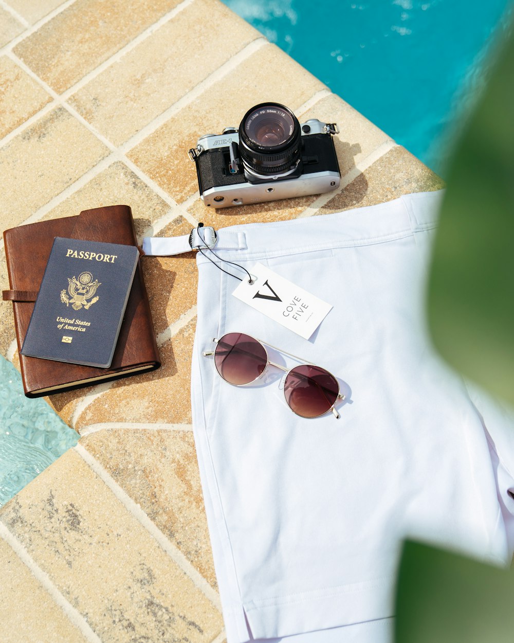 macchina fotografica a pellicola nera e grigia, passaporto e pantaloncini bianchi sul lato del sondaggio