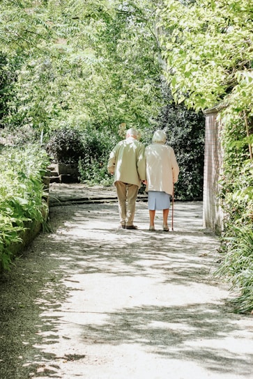 An Indian senior couple smiling warmly while enjoying a peaceful garden walk together.