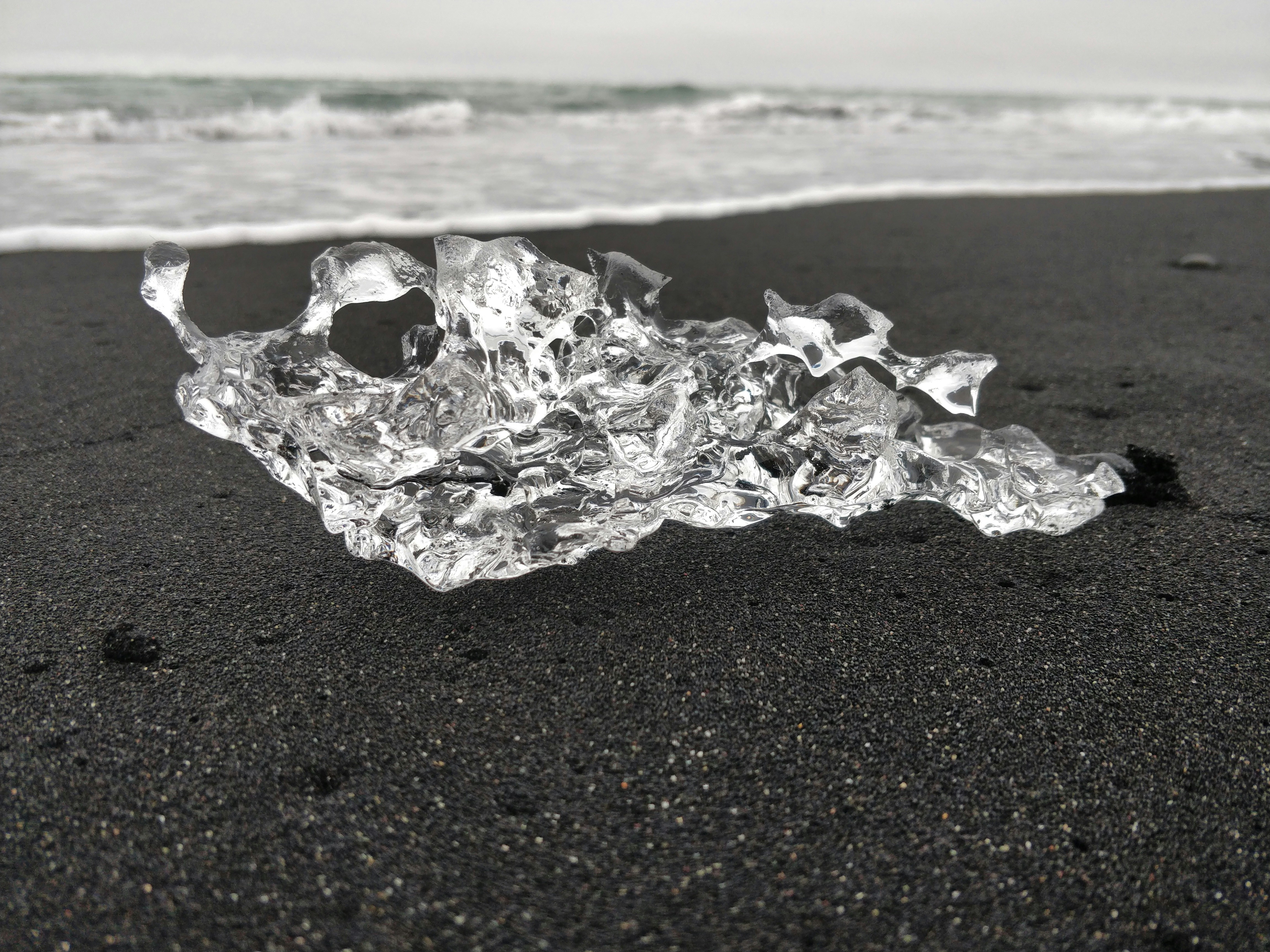 selective focus of ice formation on sand beside shore during daytime