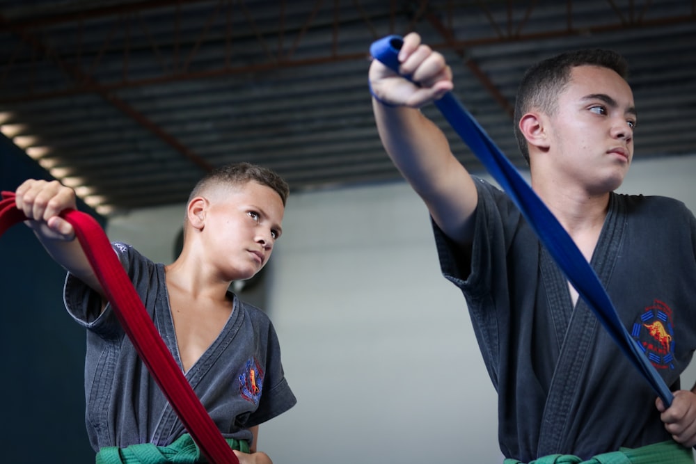 two boys posing while holding red and blue straps