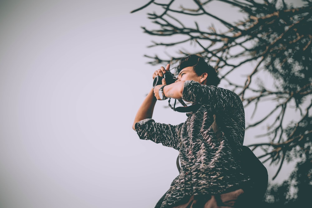 man taking photo near tree