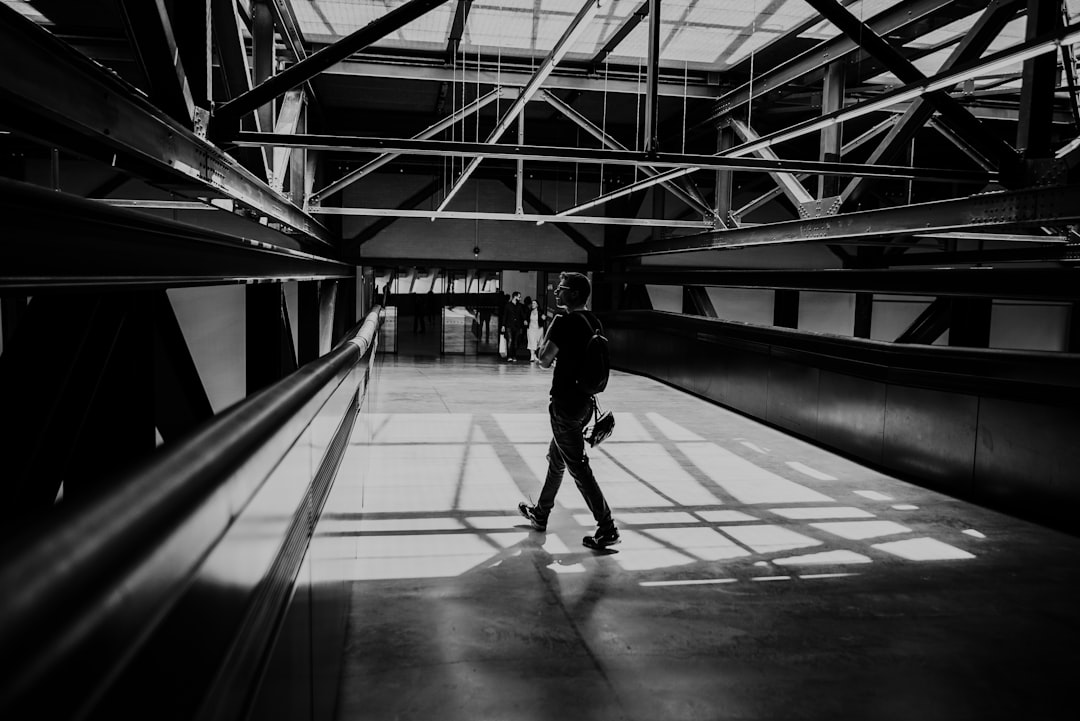 grayscale photography of man walking on pathway