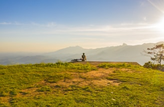 A rider pausing on a hilltop overlooking rolling hills and a serene valley at sunset