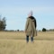 person in green jacket and blue pants standing on grass field during daytime