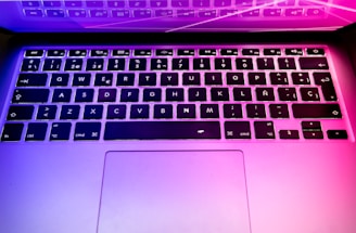 Close-up of a high-end laptop keyboard illuminated by soft purple backlighting.