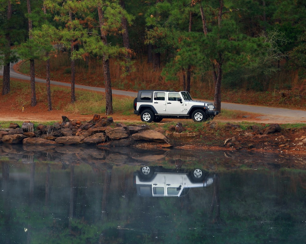 a jeep is parked on the shore of a lake