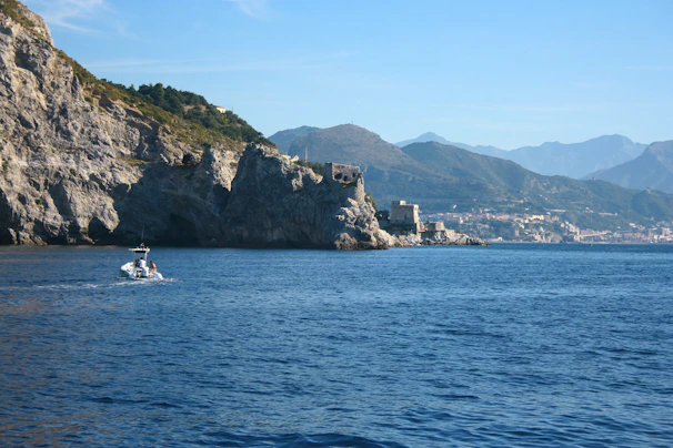 A boat sailing near the coastline with people on board admiring the sea and cliffs