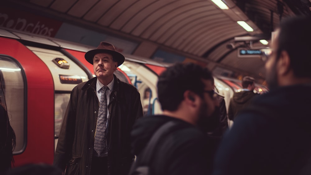 homme en chapeau brun et manteau près du train