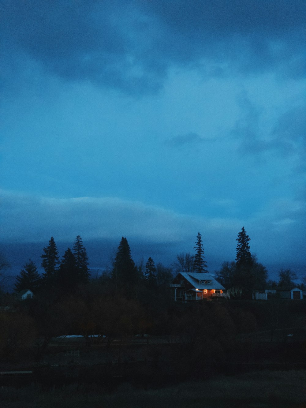 a house sitting on top of a hill under a cloudy sky