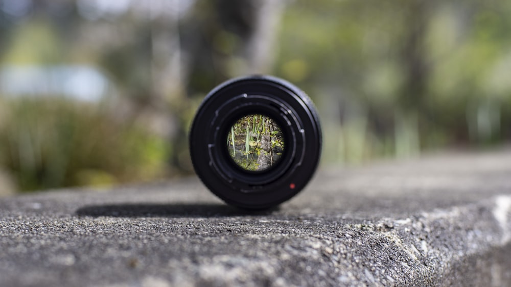 black DSLR camera lens on concrete surface