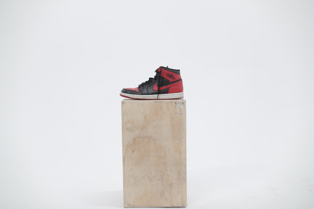 unpaired black and red Air Jordan 1 shoe on wooden box