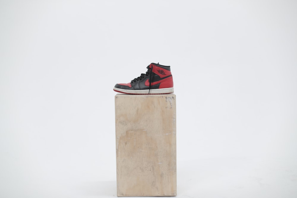 Scarpa Air Jordan 1 nera e rossa spaiata su scatola di legno