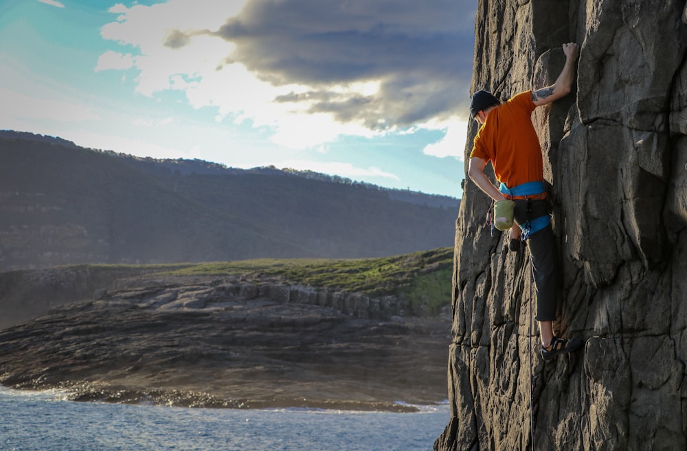 person climbing on rock formation during daytime