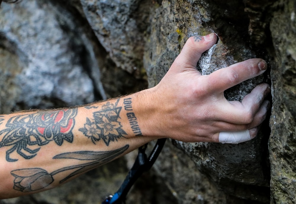a man with a tattoo on his arm holding onto a rock